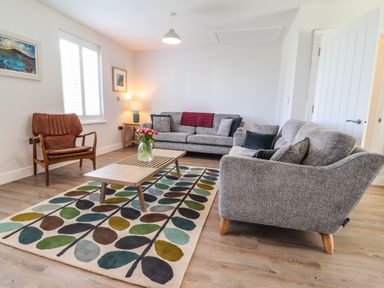 A living room with grey sofas a wooden coffee table and a floral rug at Ty Owen in Newport Pembrokeshire