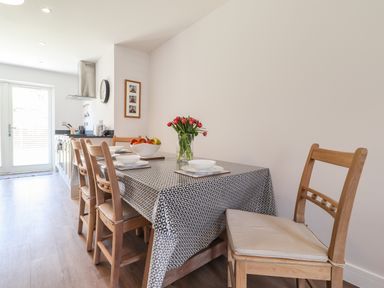 A dining area with wooden chairs around a table with a patterned tablecloth and a vase of flowers in the kitchen at Ty Owen in Newport Pembrokeshire
