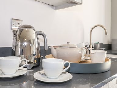 A kitchen countertop with a kettle teapot cups and a faucet at Ty Owen in Newport Pembrokeshire