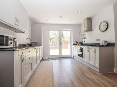 A kitchen with white cabinets black countertops a microwave toaster and wall clock at Ty Owen in Newport Pembrokeshire
