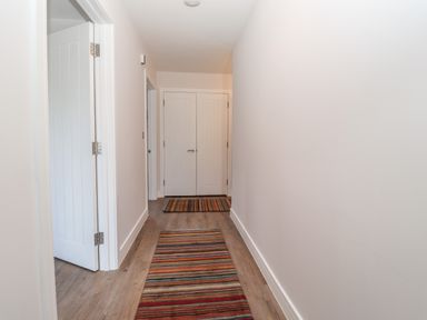 A hallway with striped rugs on wooden floor and white doors at Ty Owen in Newport Pembrokeshire