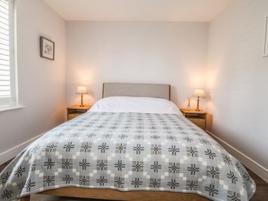 A bedroom with a bed flanked by two bedside tables and two lamps at Ty Owen in Newport Pembrokeshire