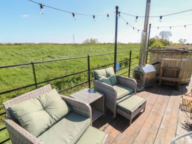 An outdoor patio with seating and a hot tub at Sweet Caroline Shepherd’s Hut in Low Marnham near Sutton-On-Trent