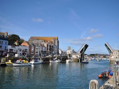 A harbor with boats docked along the quay and a raised drawbridge at Mermaid House in Brewers Quay Harbour