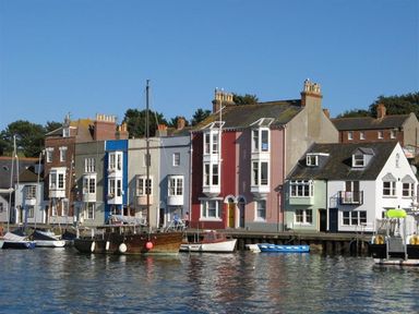 A harbor with boats docked in front of colorful houses at Mermaid House in Brewers Quay Harbour