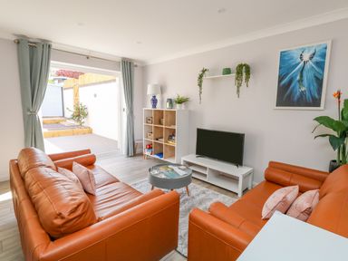 A living room with orange sofas a television on a stand and a bookshelf at Mermaid House in Brewers Quay Harbour