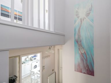 A stairwell with a mermaid painting on the wall and a view into a kitchen at Mermaid House in Brewers Quay Harbour