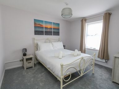 A bedroom with a bed a nightstand and a window with curtains at Mermaid House Brewers Quay Harbour