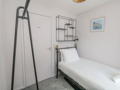 A small bedroom with a single bed a white door a wall shelf and a framed picture at Mermaid House Brewers Quay Harbour