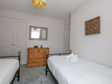 A bedroom with two single beds a wooden chest of drawers and a mirror on the wall at Mermaid House in Brewers Quay Harbour