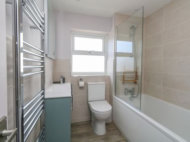 A bathroom with a toilet a bathtub with shower and a sink with cabinet at Mermaid House in Brewers Quay Harbour