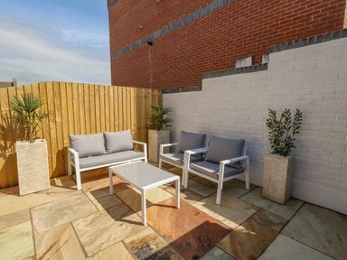 An outdoor patio with seating furniture and potted plants at Mermaid House in Brewers Quay Harbour