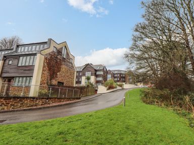 A sloped paved road with modern residential buildings on the left and trees on the right at Upper Deck in Truro