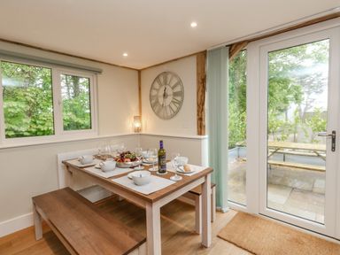 A dining area with a wooden table and benches set with bowls plates wine glass and fruit at Roman Lodge in Osmington