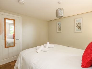 A bedroom with a bed covered in white linens and rolled towels on top with two framed pictures on the wall at Roman Lodge in Osmington
