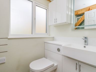 A bathroom with a toilet sink mirror and frosted window at Roman Lodge in Osmington