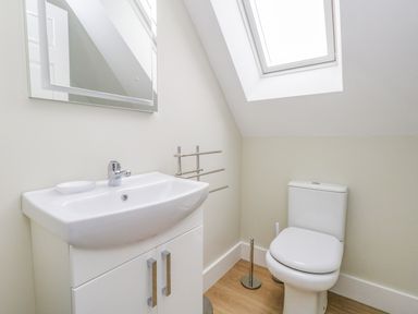 A bathroom with a sink cupboard mirror towel rack skylight and toilet at Roman Lodge in Osmington