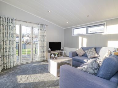 A living room with sofas coffee table television and curtains at Yealand 36 in Tewitfield