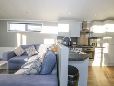 A kitchen with a sink and stove next to a living room with a sofa and cushions at Yealand 36 in Tewitfield