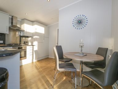 A kitchen with a round dining table and four chairs and white cabinetry at Yealand 36 in Tewitfield
