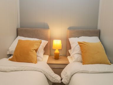 A bedroom with two single beds a bedside table and a lamp at Yealand 36 in Tewitfield