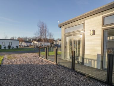 Exterior view of a modern cabin with glass railing and gravel driveway at Yealand 36 in Tewitfield