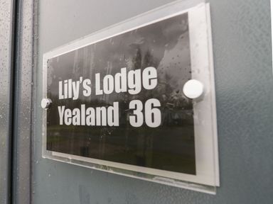 A sign on a door reading Lilys Lodge Yealand 36 at Yealand 36 in Tewitfield