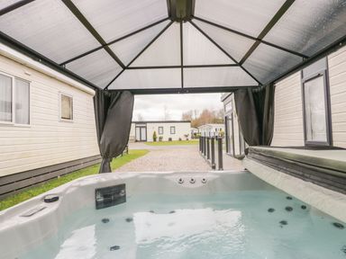 A hot tub under a canopy between two mobile homes at Yealand 36 in Tewitfield