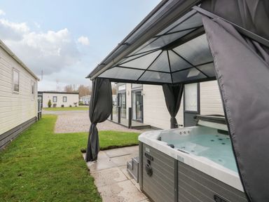 An outdoor hot tub under a gazebo next to a modern caravan at Yealand 36 in Tewitfield