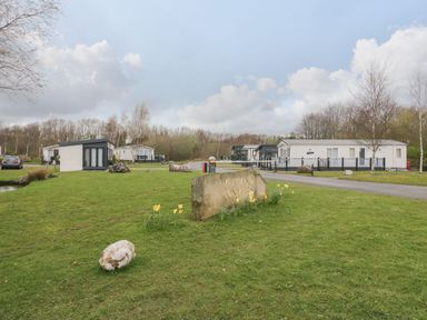 A group of mobile homes and a stone sign on a grassy area at Yealand 36 in Tewitfield