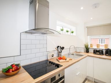 A kitchen with a stovetop sink fruit bowl and small plants at Portside Greenhill Weymouth