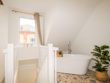 A bathroom with a bathtub next to a stairwell and a potted plant at Portside Greenhill Weymouth