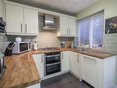A kitchen with cabinets, sink, stove, and microwave at 8 Beechwood Close Bowness-On-Windermere