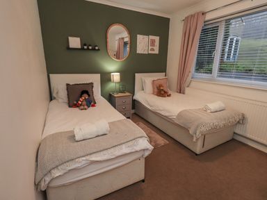 A bedroom with two beds and a nightstand at 8 Beechwood Close in Bowness-On-Windermere