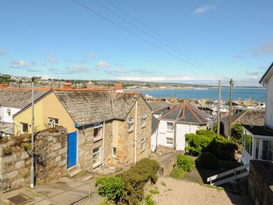 A coastal village with stone houses and a view of fishing boats in the harbor at Walter in Newlyn
