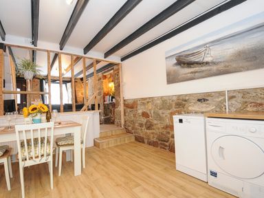 A kitchen with a dining table and chairs near stone walls and appliances at Walter in Newlyn