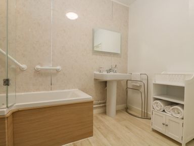 A bathroom with a bathtub sink mirror and cabinet with towels at Walter in Newlyn