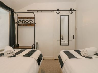 A bedroom with two single beds a hanging rail with hangers and a sliding door with a mirror at Walter in Newlyn