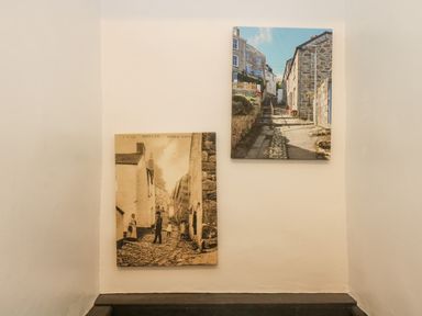 Two pictures of a narrow cobbled street with houses hanging on a white wall at Walter in Newlyn