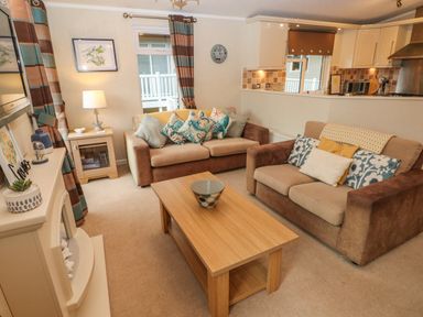 A living room with two sofas a wooden coffee table and a fireplace at 16 Heritage Park in Heritage Park near Kilgetty