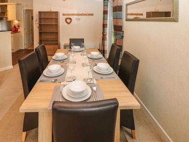 A dining room with a wooden table set for six with white dishes and wine glasses at 16 Heritage Park Heritage Park near Kilgetty