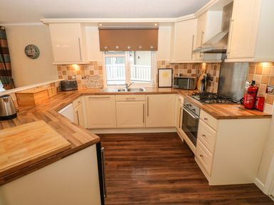 A kitchen with wooden countertops white cabinets a gas stove microwave toaster and kettle at 16 Heritage Park in Heritage Park near Kilgetty