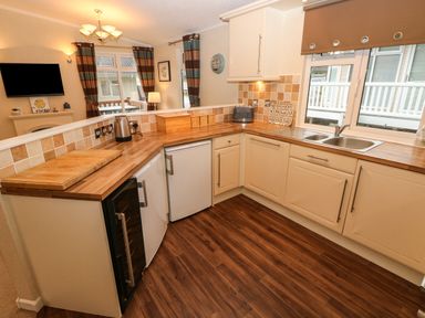 A kitchen with wooden countertops a double sink a kettle toaster and multiple cabinets at 16 Heritage Park Heritage Park near Kilgetty