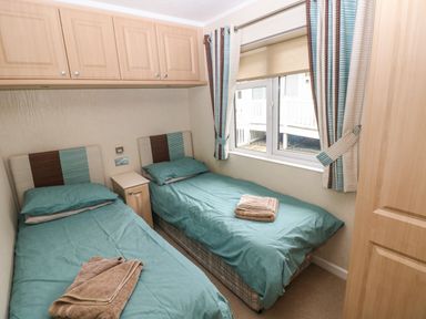 A bedroom with two single beds and a window at 16 Heritage Park in Heritage Park near Kilgetty
