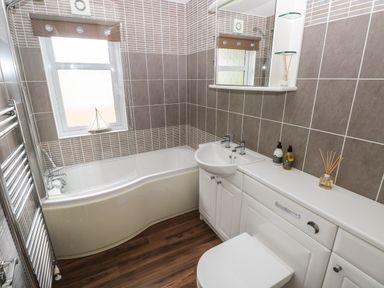 A bathroom with a bathtub toilet sink and cabinets at 16 Heritage Park Heritage Park near Kilgetty