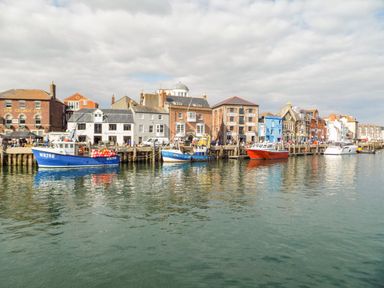 A harbor with boats docked in front of buildings along the waterfront at Amaranta Brewers Quay Harbour