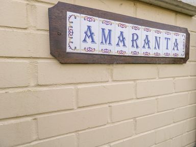 A decorative tile sign with the word Amaranta mounted on a beige brick wall at Amaranta Brewers Quay Harbour