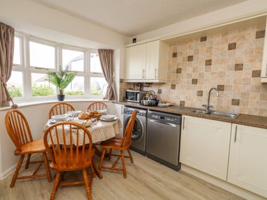 A kitchen with wooden chairs around a table set with plates and bread at Amaranta Brewers Quay Harbour