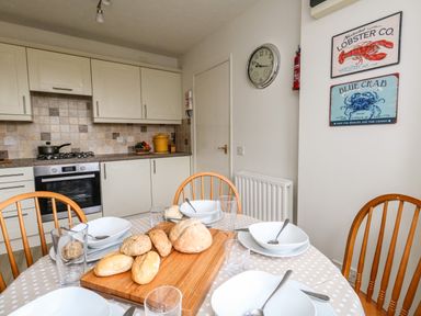 A kitchen with a dining table set with bowls spoons and glasses and bread rolls on a wooden board at Amaranta in Brewers Quay Harbour