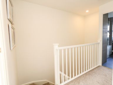 A landing area with white railing and carpeted floor near a bathroom with dark tiles at Amaranta Brewers Quay Harbour